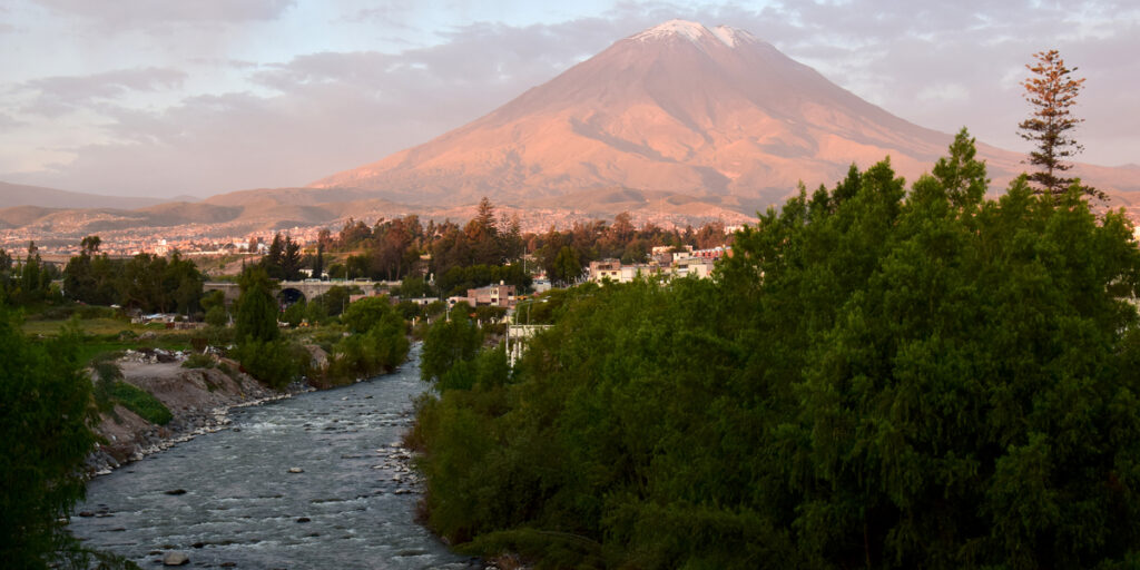 The Chili River winds through a rugged canyon near Arequipa, its white rapids crashing against rocks as it flows beneath volcanic hills, a popular spot for white water rafting just outside the city.