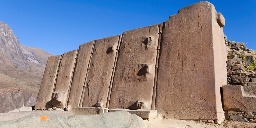 Massive stone blocks of the Sun Temple at Ollantaytambo, precisely fitted together atop a terraced platform with mountain views in the background.