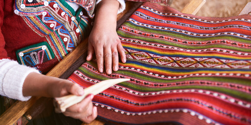 Close-up of a woman’s hands skillfully weaving Andean textiles using traditional techniques and colorful threads.”