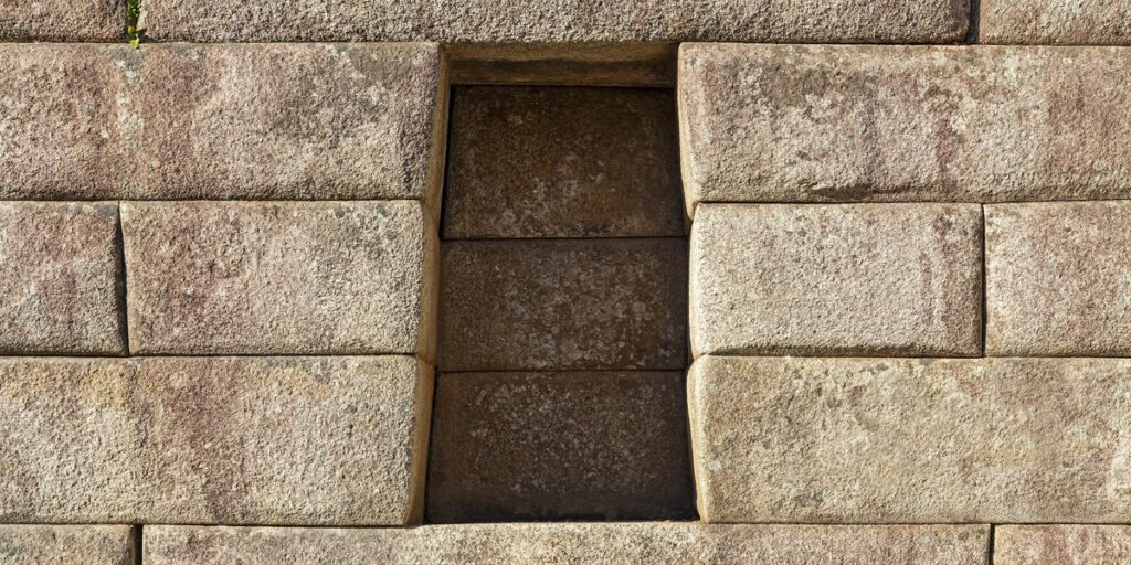 Close-up view of trapezoid-shaped stone windows at Machu Picchu, expertly carved and fitted together using precisely cut stones with no visible mortar between the joints.