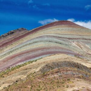 The colorful, stratified slopes of Palccoyo Rainbow Mountain in Peru, showing layers of red, yellow, and greenish minerals
