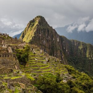 A panoramic view of the ancient stone ruins of Machu Picchu, showcasing its terraced slopes, temples, and precisely crafted walls nestled high among the green Andean mountains.